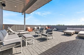 a patio with lounge chairs and couches on top of a building